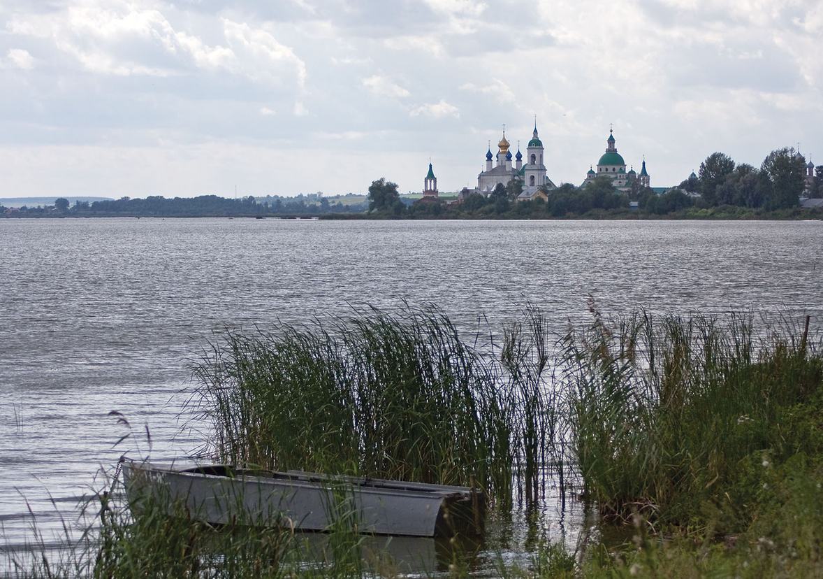 Заросший камышом берег озера Неро с лодкой и куполами Ростова на горизонте