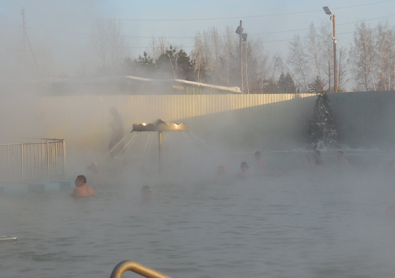Открытый термальный бассейн под Тюменью зимой, пар над водой